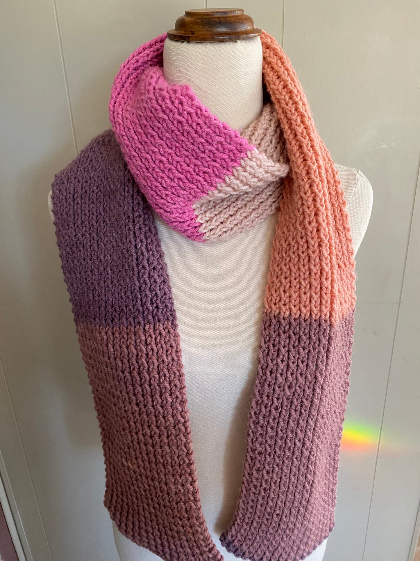 Knitted scarf with pink and purple gradient on a mannequin against a white background